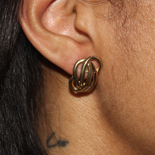 Close-up of an ear wearing a gold hoop earring with a blurred background
