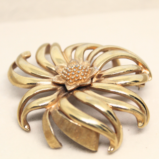 Gold brooch with a star-like center on a beige background