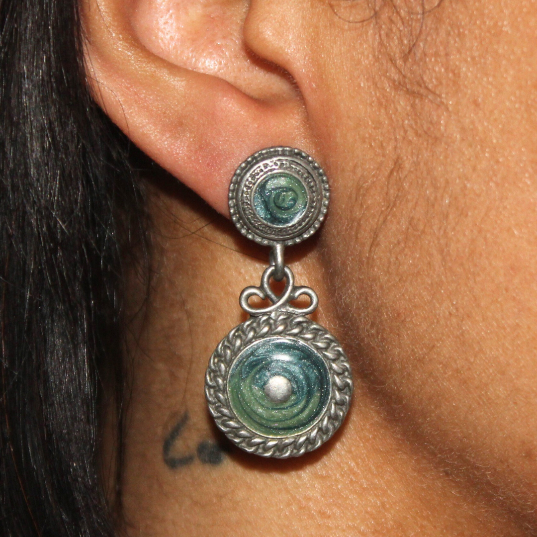 Close-up of an ear wearing a silver earring with greenstone stones.