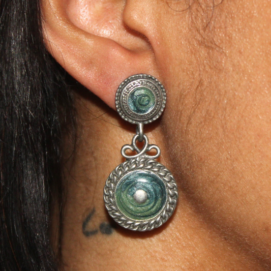 Close-up of an ear wearing a silver earring with greenstone stones.