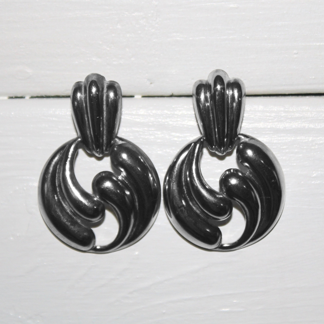 Pair of silver earrings on a light wooden background