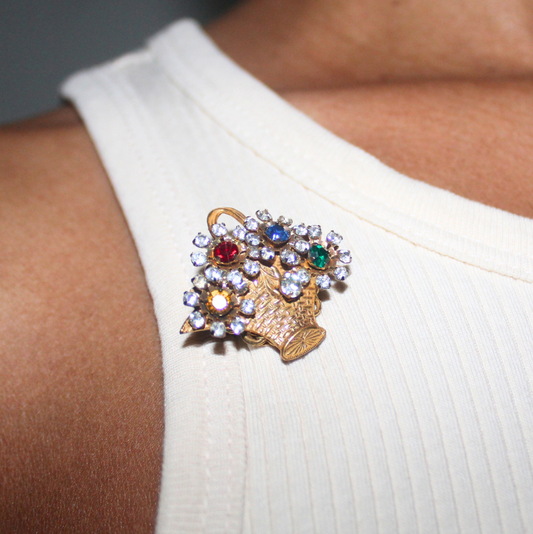 Close-up of a person wearing a white dress with a decorative brooch on a plain background