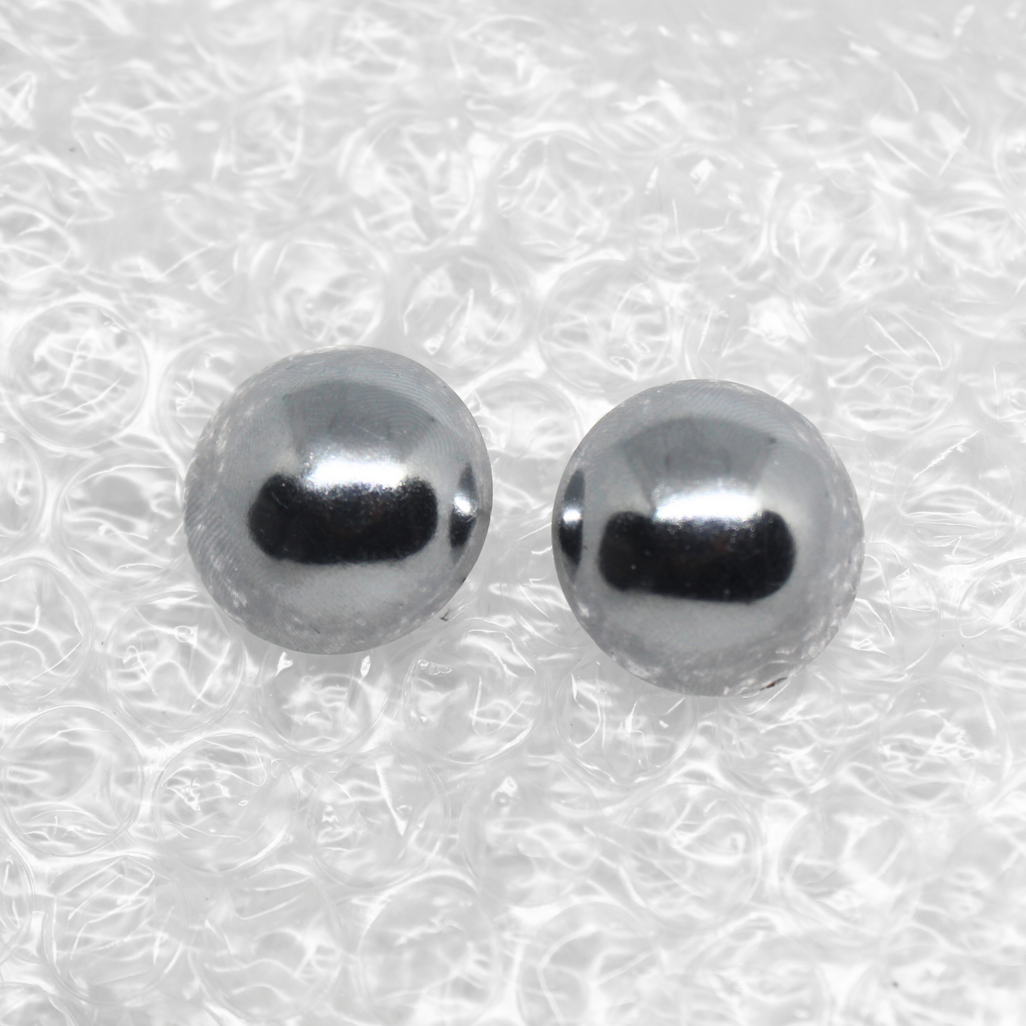 Pair of silver stud earrings on a textured white background