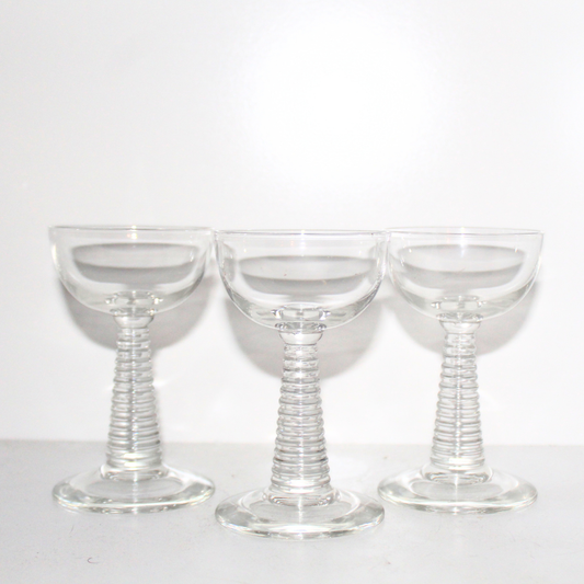 Three clear glass goblets with spiral stems on a white background