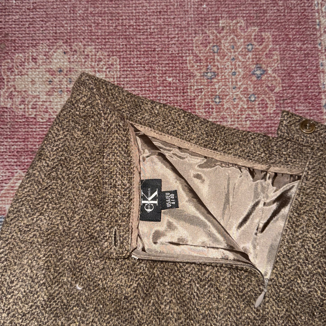 Close-up of a brown fabric with a brand label on a textured pink background