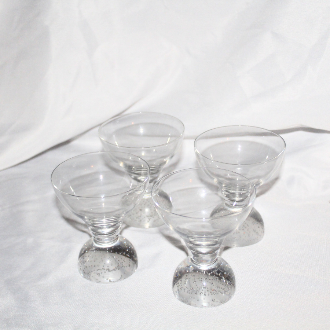 Set of four clear glass dessert dishes on a white background