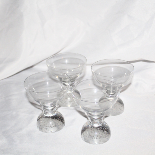 Set of four clear glass dessert dishes on a white background