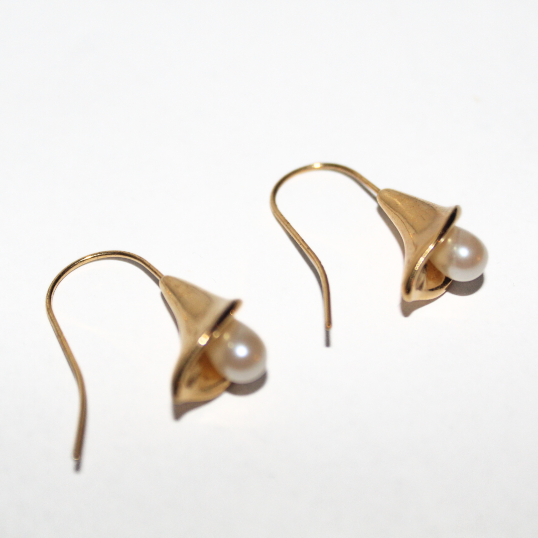 Gold earrings with pearl drops on a white background