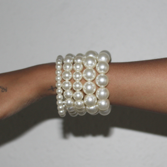 Pearl bracelet on a wrist against a plain background