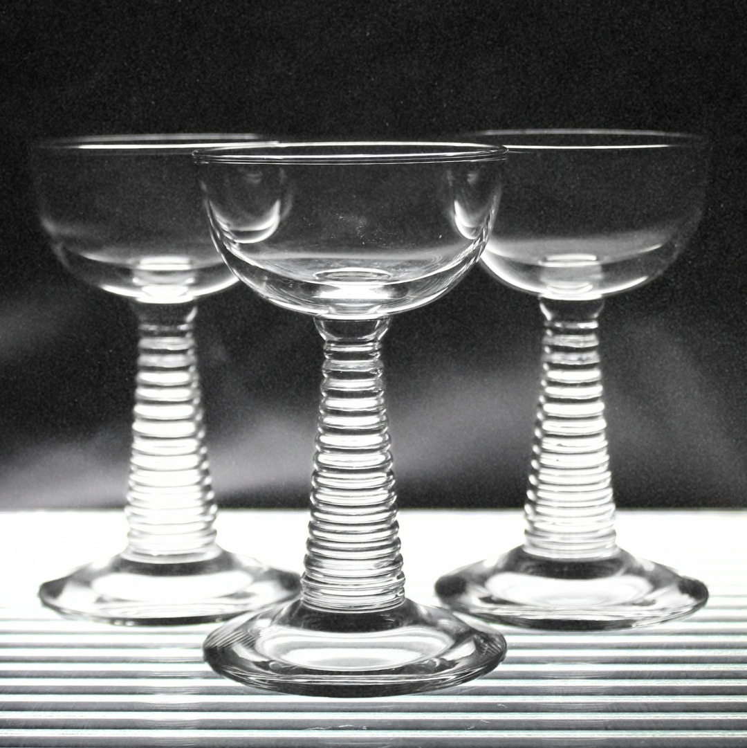 Three clear glass stemware with spiral designs on a black background