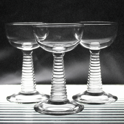 Three clear glass stemware with spiral designs on a black background