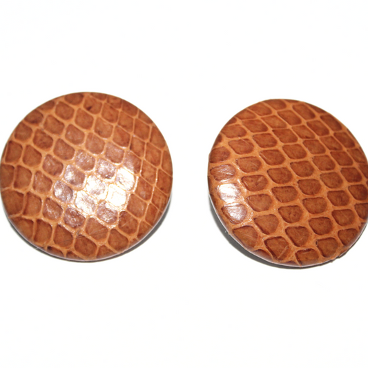 Pair of brown crocodile skin patterned buttons on a white background