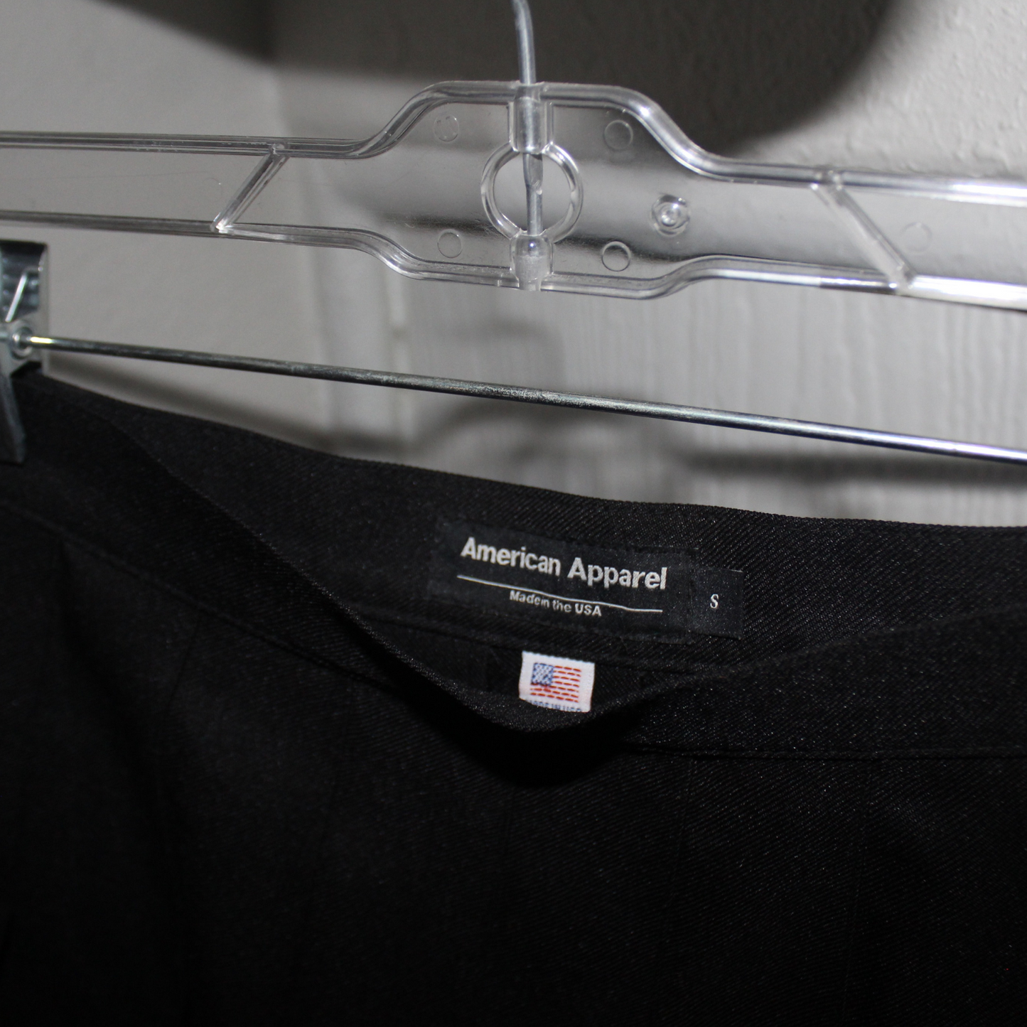 Black t-shirt with American Apparel label on a clear hanger.