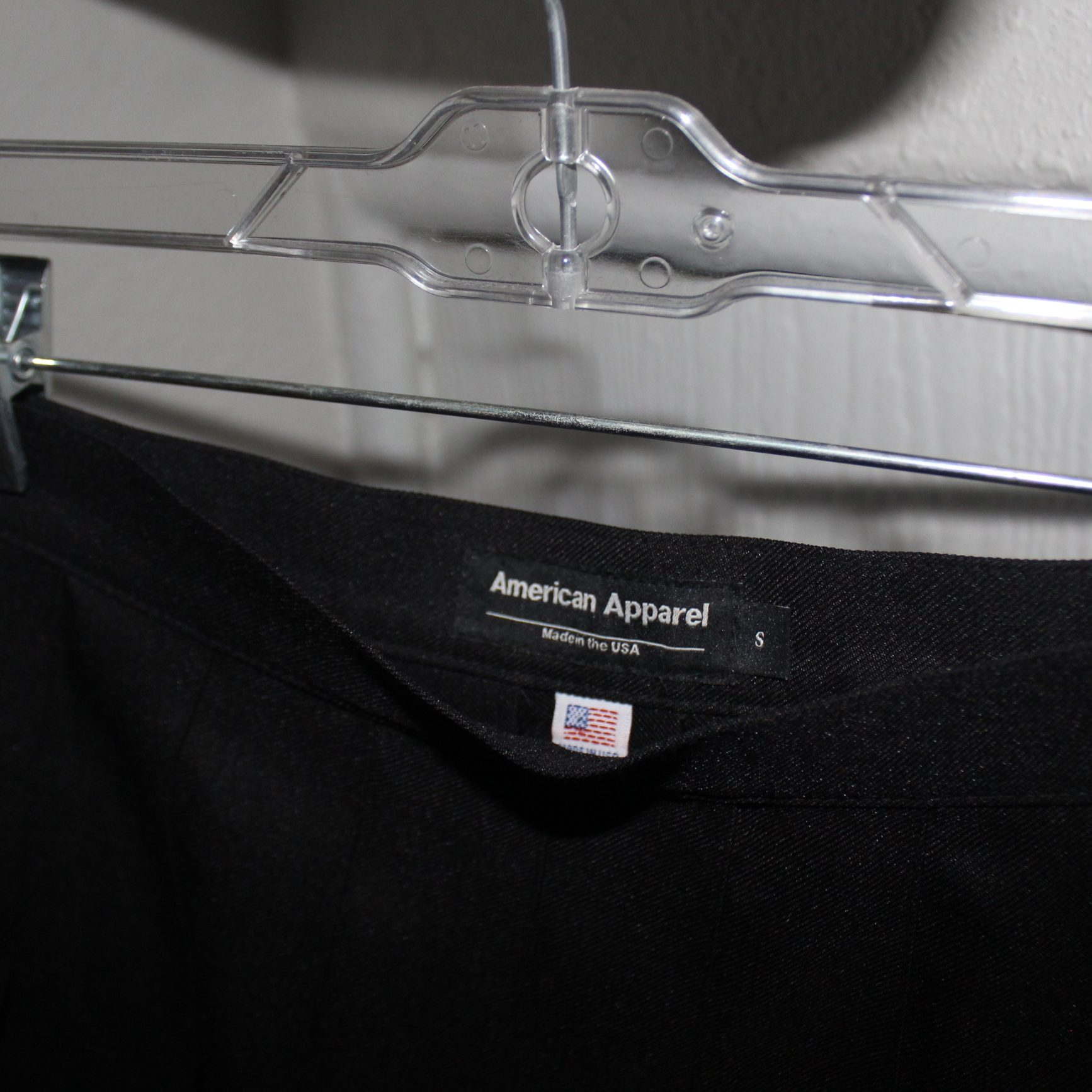 Black t-shirt with American Apparel label on a clear hanger.