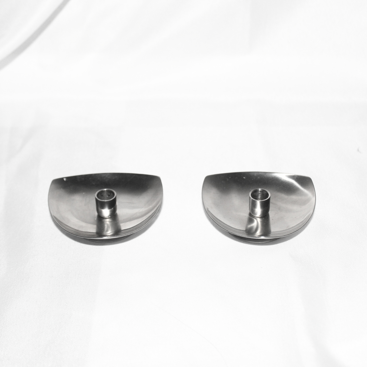 Two silver candle holders on a white background