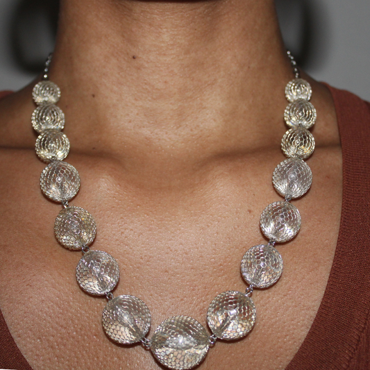Silver beaded necklace on a person with a blurred background