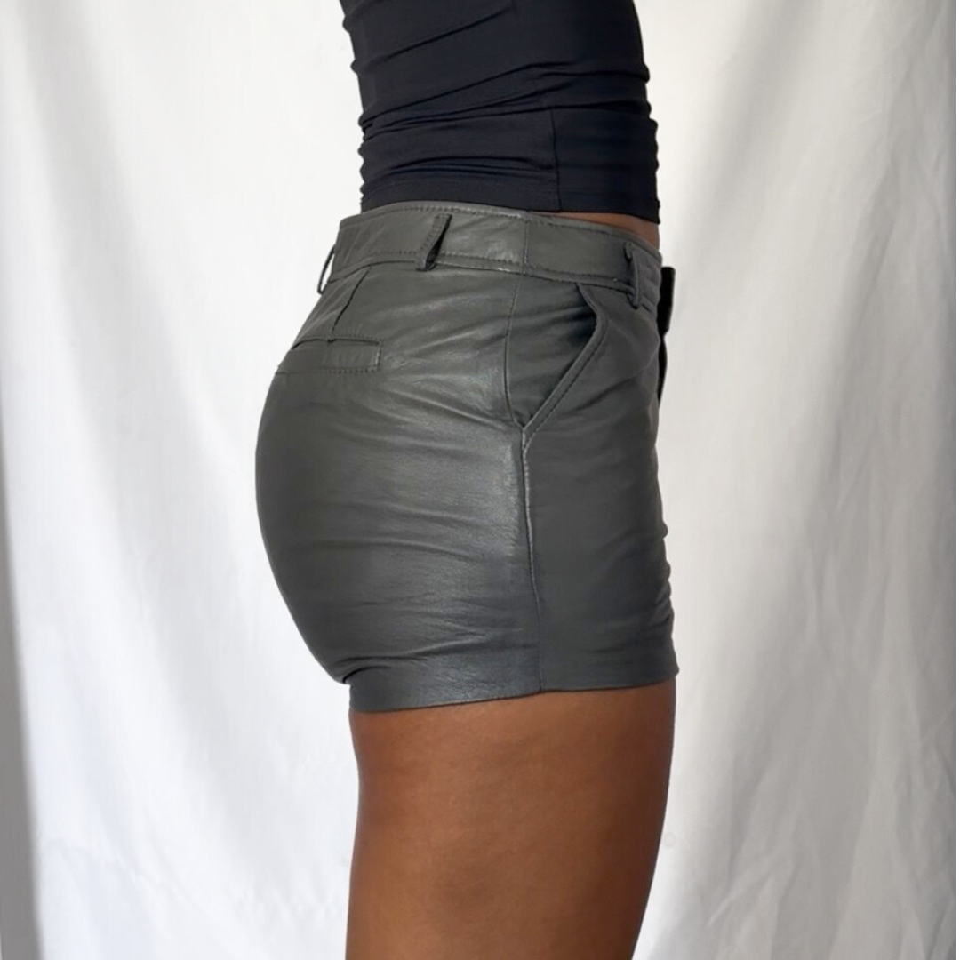 Gray leather shorts worn by a person on a white background