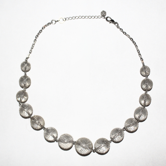 Silver necklace with round textured beads on a white background