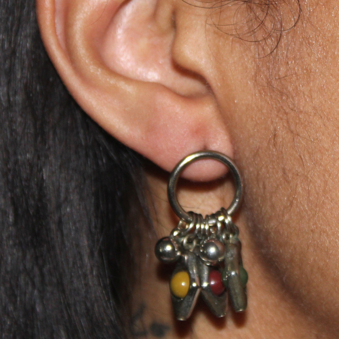 Close-up of an ear with a silver hoop earring featuring colorful beads.
