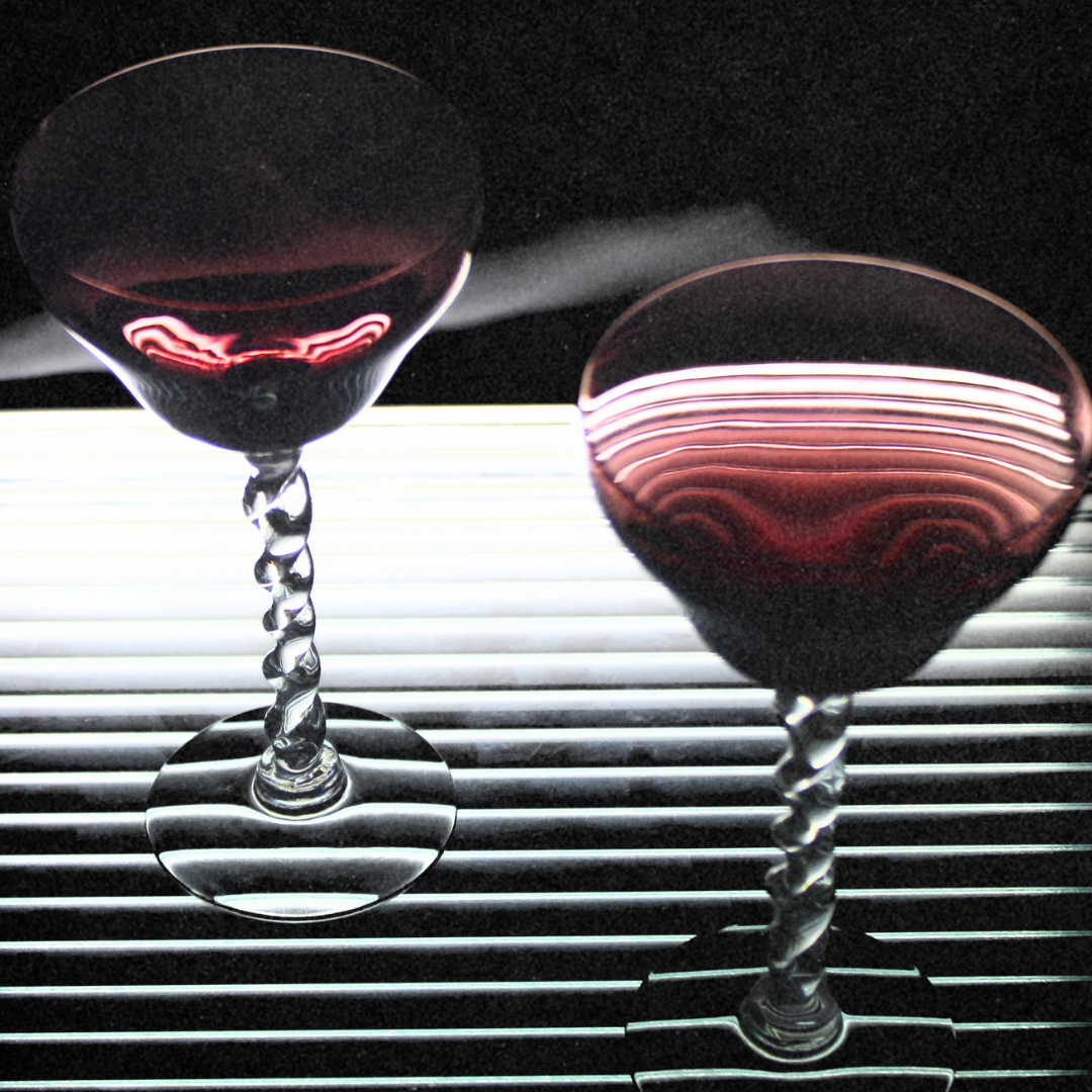 Two martini glasses with red cocktails on a car dashboard
