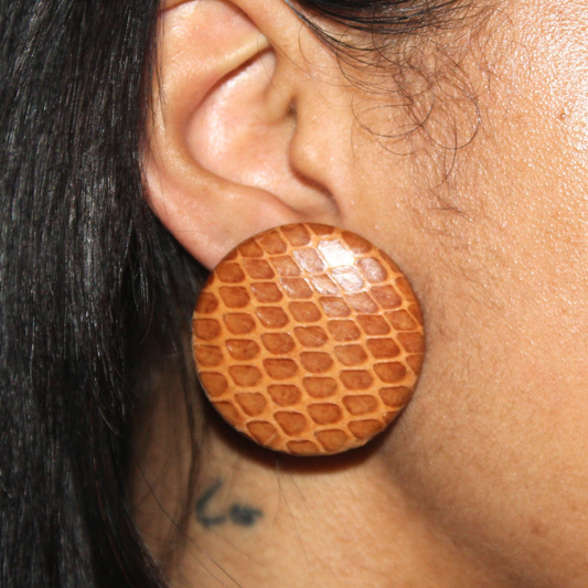 Close-up of an ear wearing a round, brown textured earring.